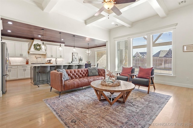 living room with beam ceiling, light wood-type flooring, and a ceiling fan