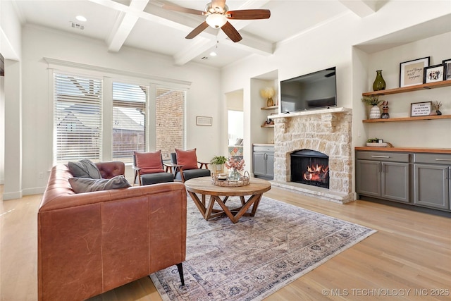 living room with visible vents, beam ceiling, light wood-style floors, and a fireplace