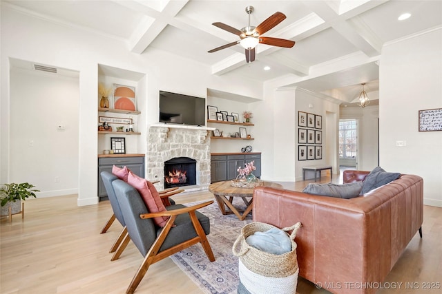 living area featuring a stone fireplace, light wood-style flooring, coffered ceiling, and ceiling fan