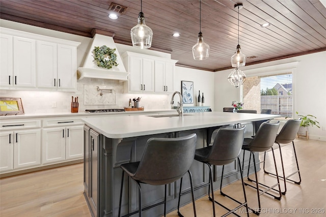 kitchen with crown molding, wood ceiling, visible vents, and a sink