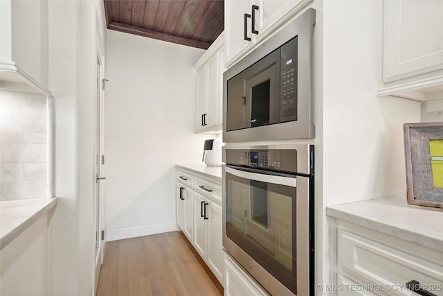 kitchen with white cabinetry, wooden ceiling, built in microwave, and oven