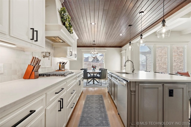 kitchen with custom range hood, a sink, appliances with stainless steel finishes, wooden ceiling, and light countertops