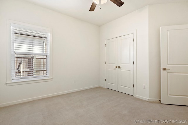 unfurnished bedroom featuring light colored carpet, baseboards, a closet, and ceiling fan