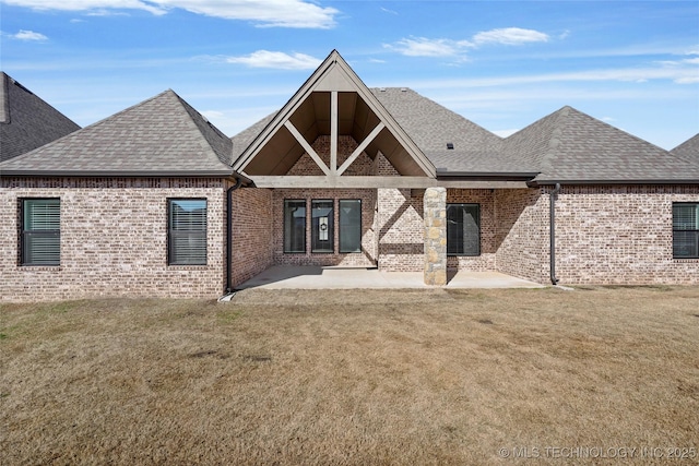 back of house with a patio, a lawn, and brick siding