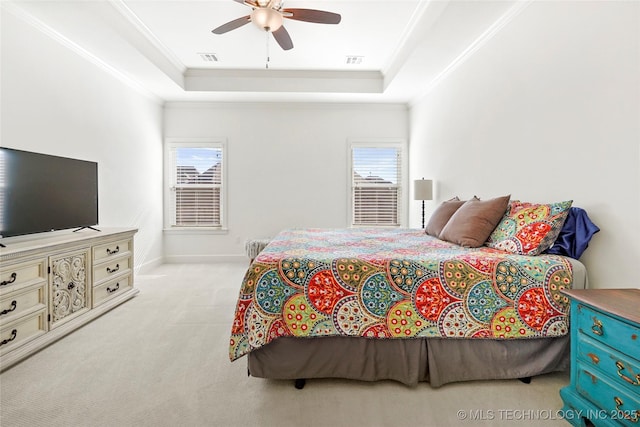 bedroom featuring a tray ceiling, multiple windows, and ornamental molding