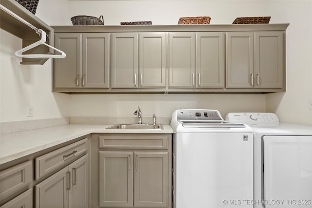 washroom with washing machine and clothes dryer, cabinet space, and a sink