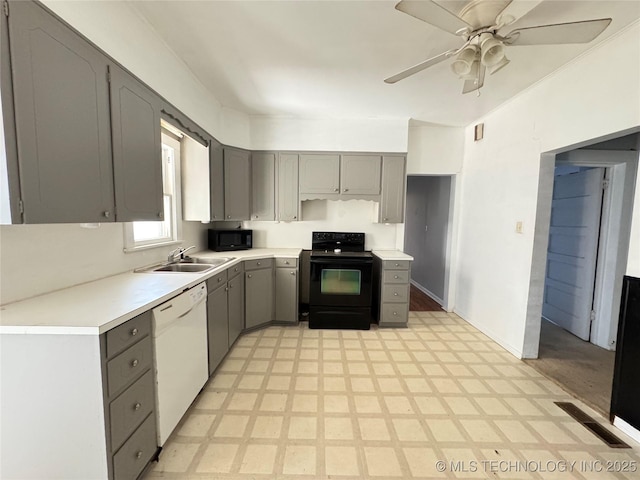 kitchen featuring visible vents, black appliances, gray cabinets, a sink, and light floors