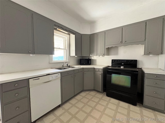 kitchen featuring black appliances, light floors, gray cabinets, and a sink