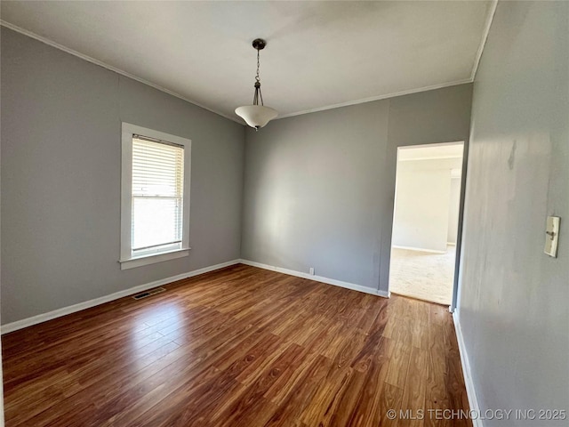 spare room with crown molding, wood finished floors, and baseboards