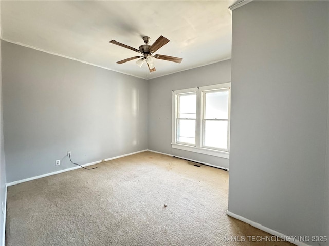 carpeted spare room with crown molding, baseboards, visible vents, and ceiling fan