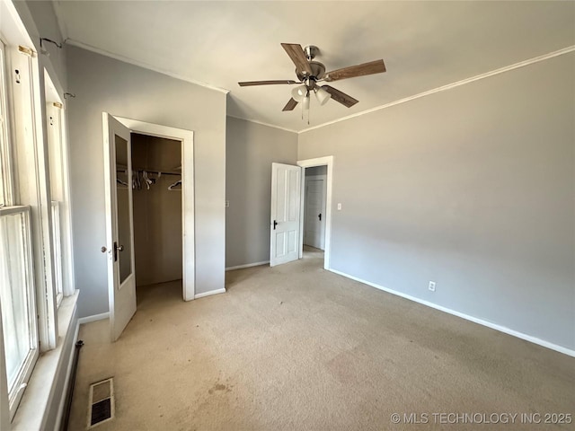 unfurnished bedroom featuring visible vents, baseboards, ornamental molding, light carpet, and a closet