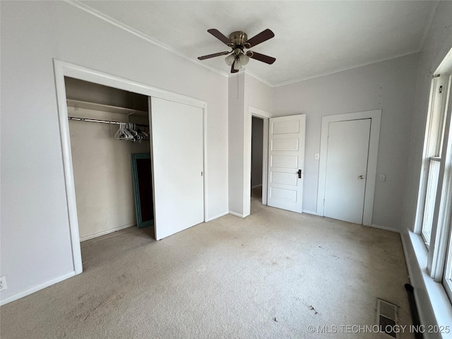 unfurnished bedroom featuring visible vents, a closet, carpet, crown molding, and ceiling fan