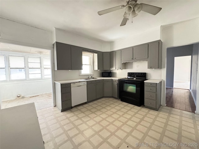 kitchen with black appliances, gray cabinetry, a sink, light countertops, and light floors