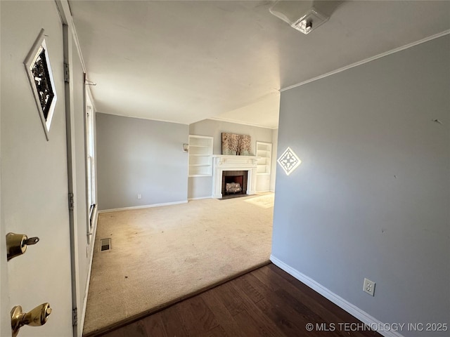 unfurnished living room featuring visible vents, wood finished floors, carpet floors, baseboards, and a tile fireplace