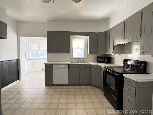 kitchen featuring gray cabinetry, light floors, light countertops, black appliances, and a sink