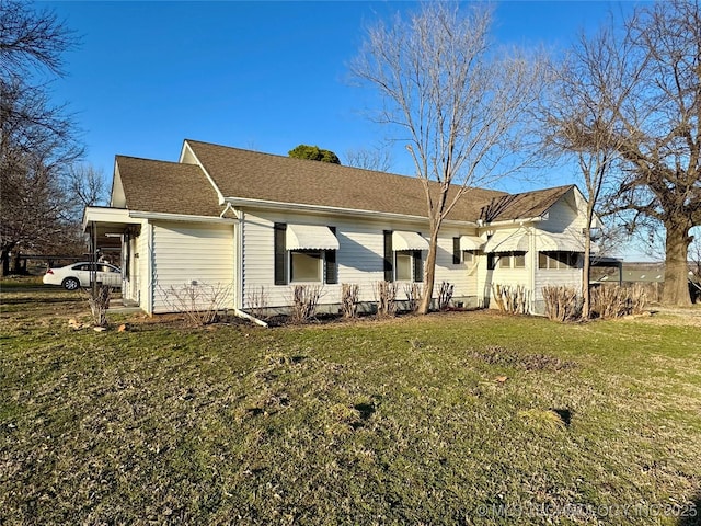 back of property with a yard and roof with shingles