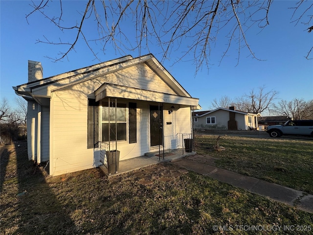 bungalow-style home with a front yard and a chimney