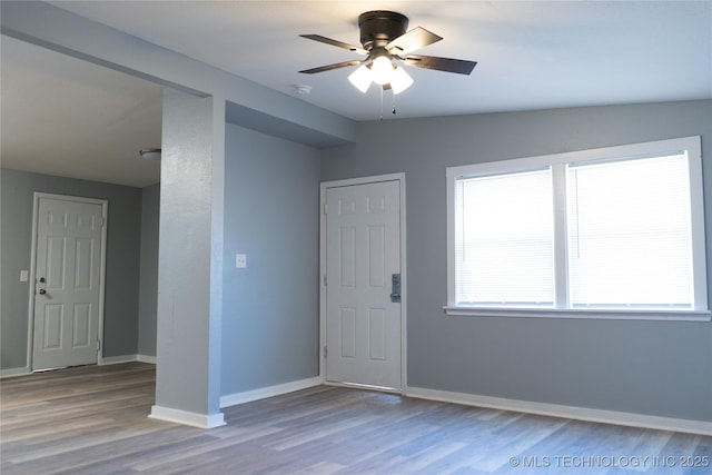 unfurnished room with a ceiling fan, wood finished floors, and baseboards