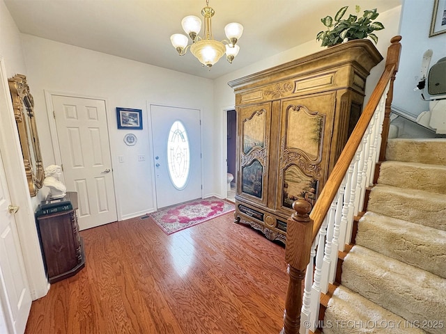 foyer entrance featuring a notable chandelier, stairs, and wood finished floors