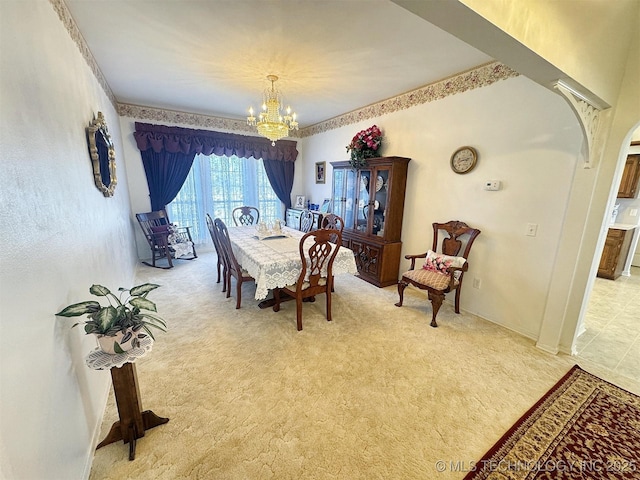 dining space featuring a notable chandelier, arched walkways, and light carpet