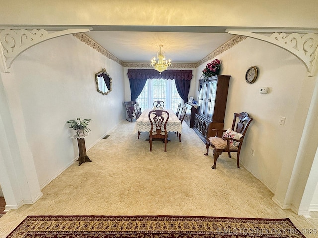 dining space with a notable chandelier, visible vents, arched walkways, and light carpet