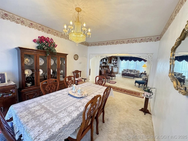 carpeted dining area featuring arched walkways and an inviting chandelier