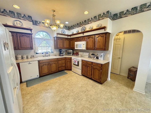 kitchen featuring arched walkways, white appliances, light countertops, and a sink