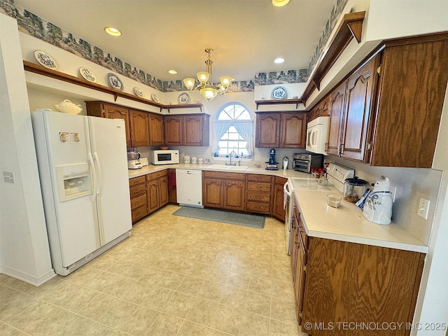 kitchen with white appliances, light countertops, a chandelier, and a sink