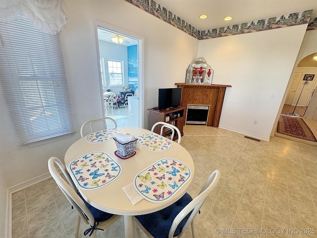 dining room with visible vents, baseboards, recessed lighting, a fireplace, and arched walkways