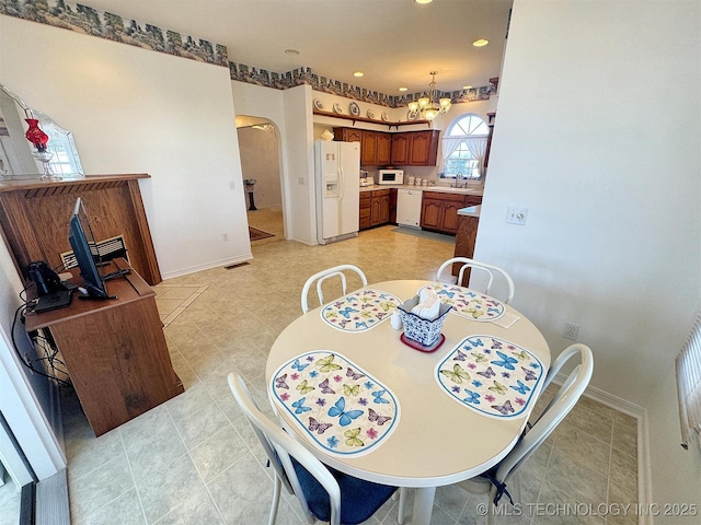 dining space with arched walkways, a chandelier, recessed lighting, and baseboards