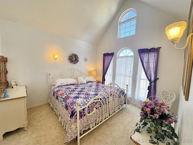 bedroom with light colored carpet, baseboards, and high vaulted ceiling