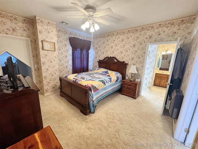 bedroom featuring visible vents, wallpapered walls, ceiling fan, ensuite bathroom, and light colored carpet