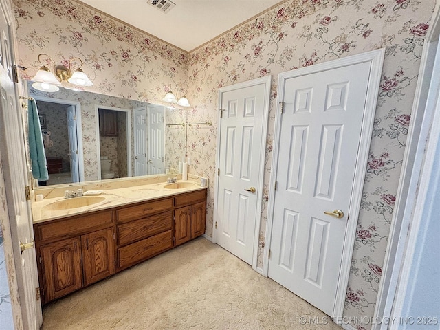 full bathroom featuring wallpapered walls, double vanity, visible vents, and a sink