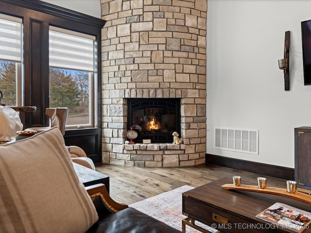 living room featuring visible vents, a fireplace, and wood finished floors