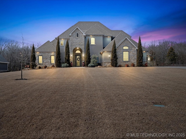 french country style house featuring stone siding and stucco siding