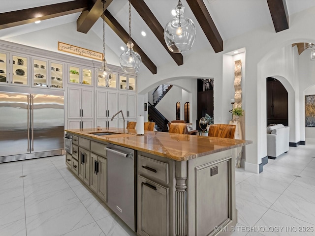 kitchen featuring marble finish floor, arched walkways, appliances with stainless steel finishes, and a sink