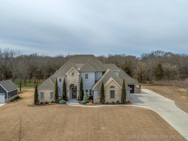 view of front of home with concrete driveway, stone siding, and a shingled roof