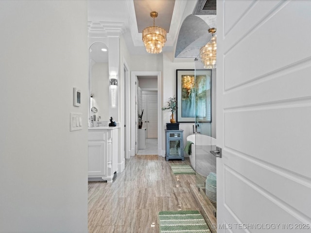 hall with baseboards, light wood-type flooring, and a chandelier