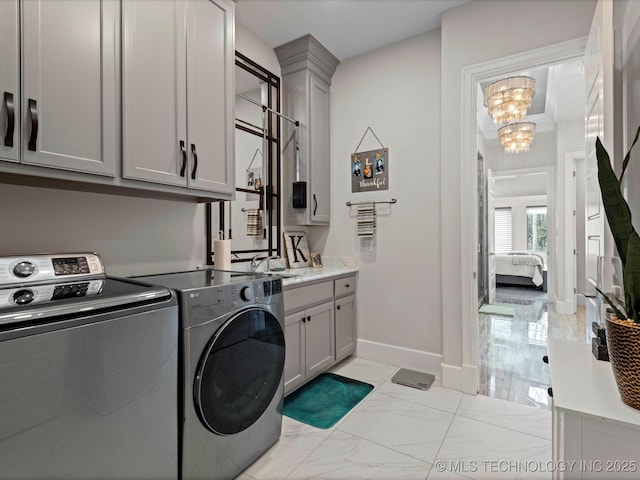 laundry room with baseboards, cabinet space, washer and dryer, marble finish floor, and a chandelier