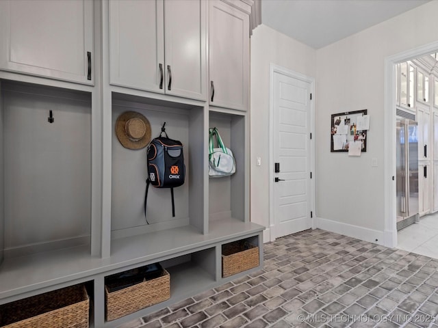 mudroom featuring brick floor and baseboards