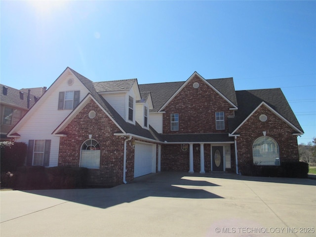 traditional-style home with a garage, brick siding, driveway, and a shingled roof