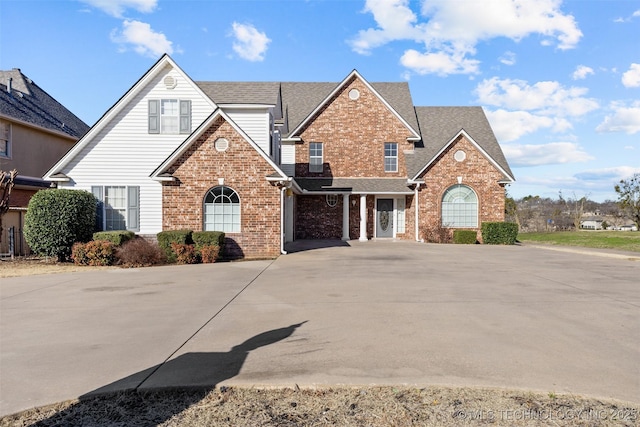 traditional home featuring brick siding, concrete driveway, and a shingled roof