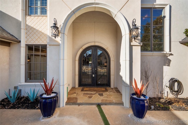 view of exterior entry featuring french doors and stucco siding