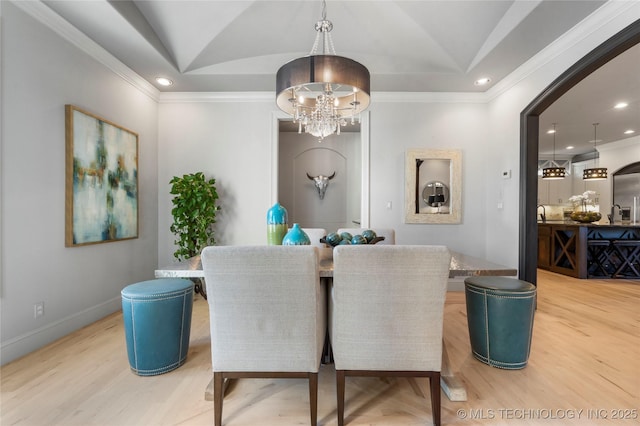 dining space with a tray ceiling, a notable chandelier, wood finished floors, and ornamental molding