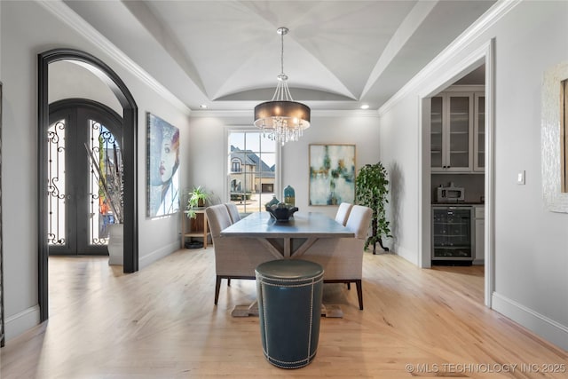 dining space with beverage cooler, arched walkways, baseboards, and light wood-style floors