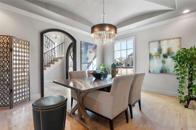 dining area with light wood-type flooring, stairway, arched walkways, and baseboards