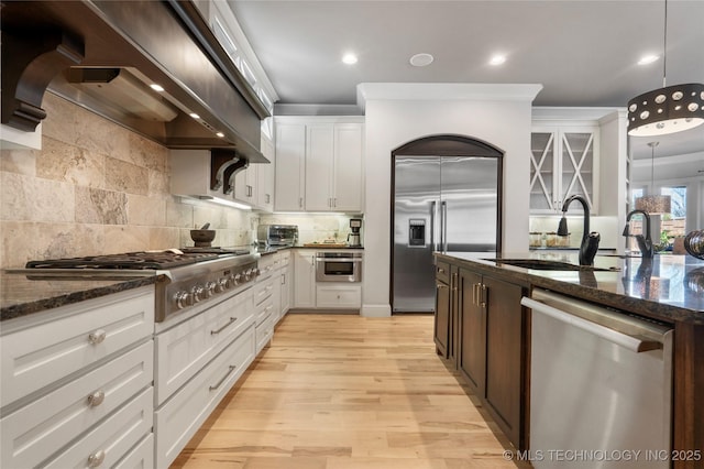 kitchen featuring a sink, dark stone countertops, tasteful backsplash, stainless steel appliances, and white cabinets