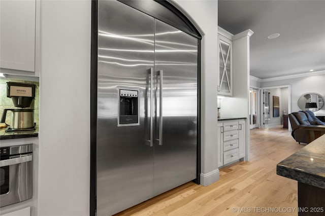 kitchen with ornamental molding, open floor plan, white cabinetry, light wood-style floors, and appliances with stainless steel finishes