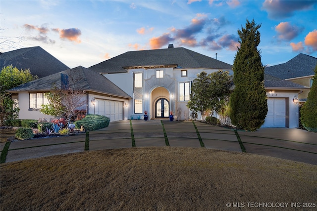 view of front of house with french doors, a garage, driveway, and stucco siding