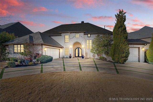 french country home featuring french doors, a garage, concrete driveway, and stucco siding